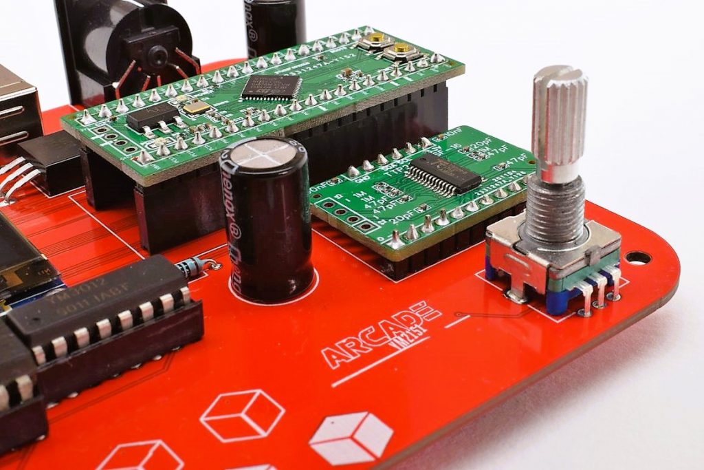 Close-up of the red DAFM Arcade circuit board with a green microcontroller module and a rotary encoder