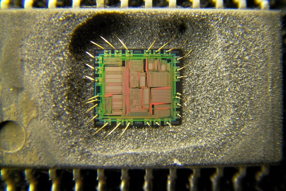 Decapsulated Yamaha YMF262 OPL3 chip under a microscope, with the silicon die and gold bond wires exposed in its package