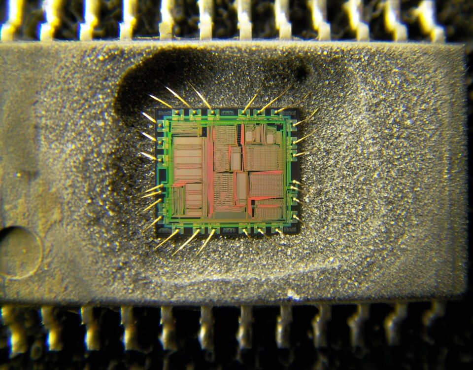 Decapsulated Yamaha YMF262 OPL3 chip under a microscope, with the silicon die and gold bond wires exposed in its package