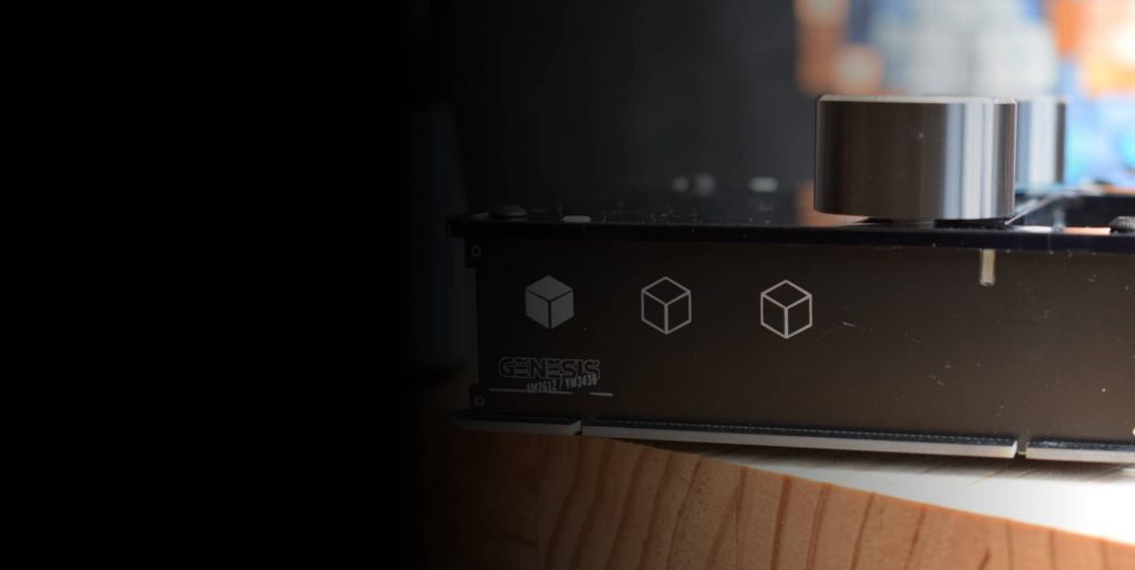 Side of the black DAFM Genesis case with the Genesis logo, cube graphics and a silver knob on a wooden table